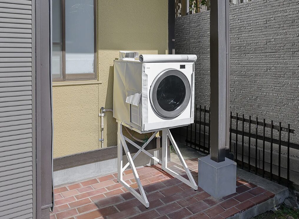 屋外の住宅外壁横に専用架台で設置されたガス衣類乾燥機。排気ダクトが接続された屋外設置例。