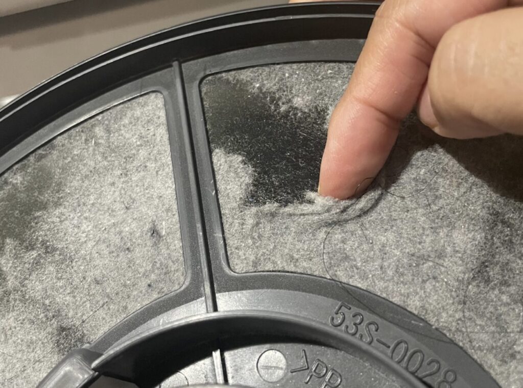 乾太くんの糸くずフィルター表面に大量のホコリが付着している様子。指でめくると厚く堆積している状態の接写。