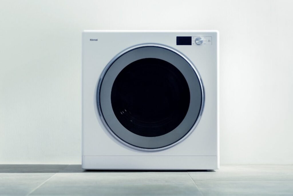 白い壁面に設置されたリンナイ製ガス衣類乾燥機の正面イメージ。シンプルなスクエアデザインと丸型ドアが特徴的な外観。