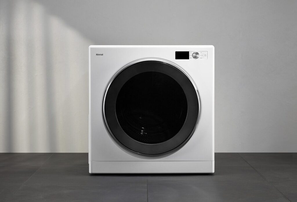 白い壁とグレーの床のシンプルな空間に設置されたリンナイ製のドラム式ガス衣類乾燥機。正面に大きなブラックガラスドアと操作パネルが配置されたミニマルデザインの外観。