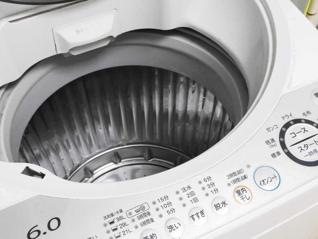 フタを開けた縦型洗濯機の空の洗濯槽。操作パネルとステンレス槽内部が見える状態で、洗濯前の準備段階。