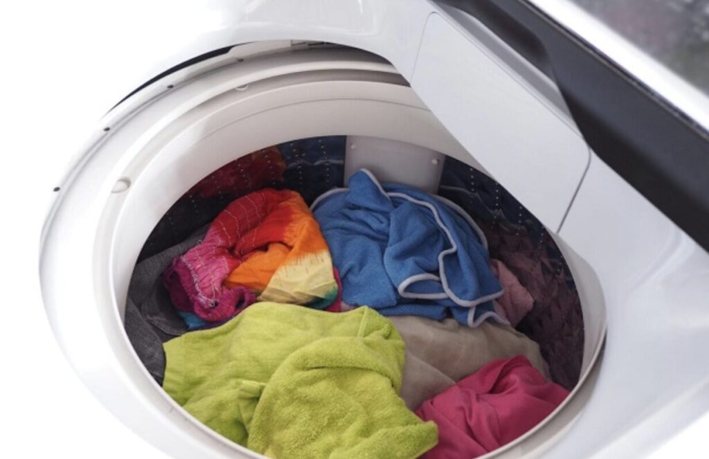 上開き式洗濯機の内部にカラフルな衣類やタオルが入っている状態の様子。