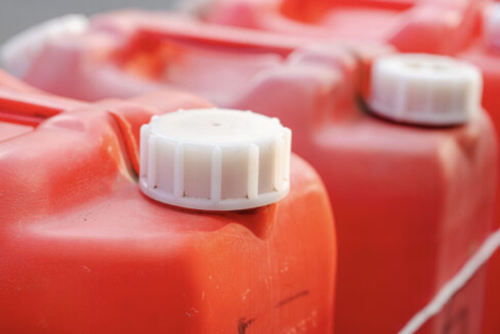 赤いポリタンクのキャップ部分をクローズアップした写真。複数の灯油容器が並んでいる。