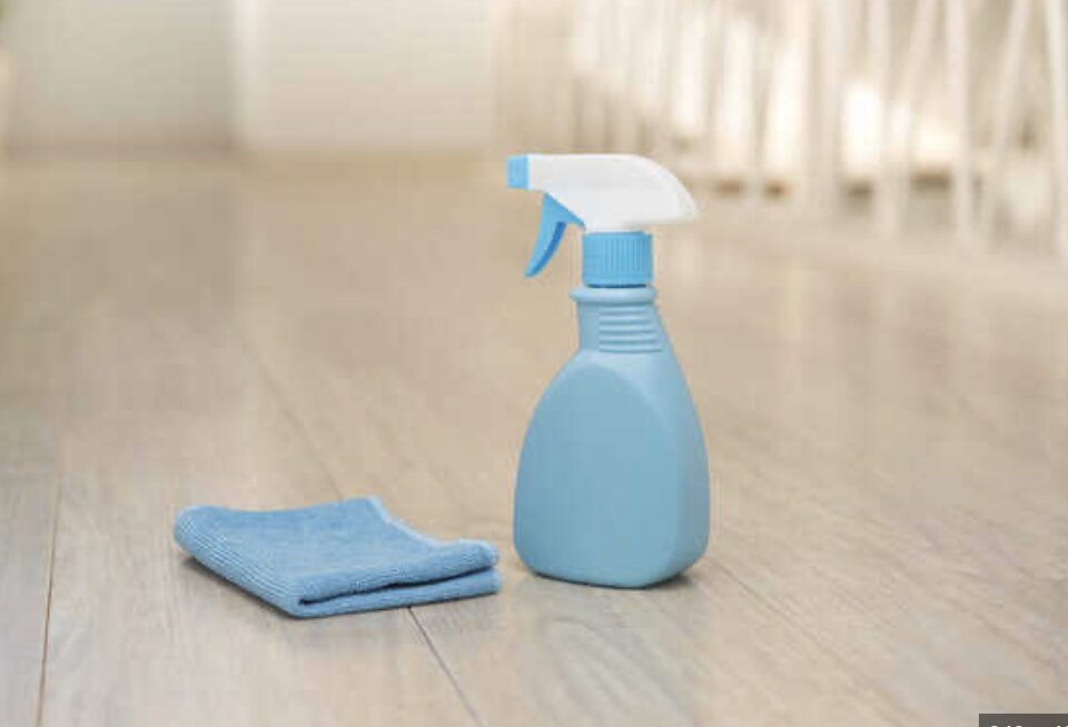フローリングの床に置かれた青いスプレーボトルとマイクロファイバークロス。室内清掃をイメージした構図。