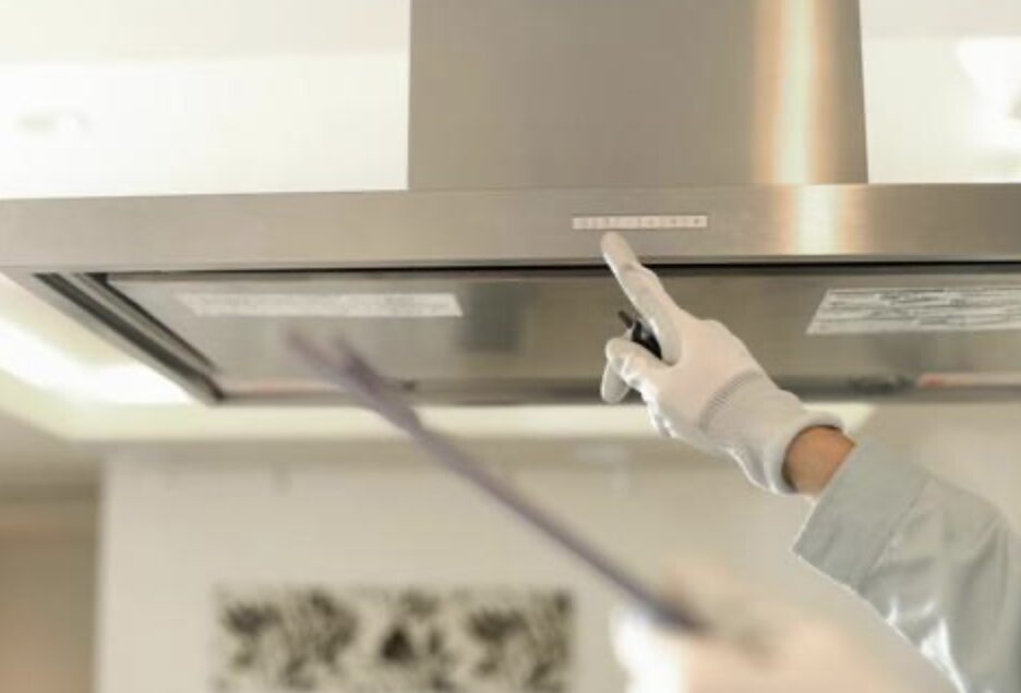 レンジフード本体を取り外し、電動ドライバーで固定部を外している施工中の様子。