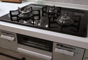 ガラストップ仕様のビルトインガスコンロを斜め上から撮影した写真。三口バーナーとグリル付きの一体型タイプ。