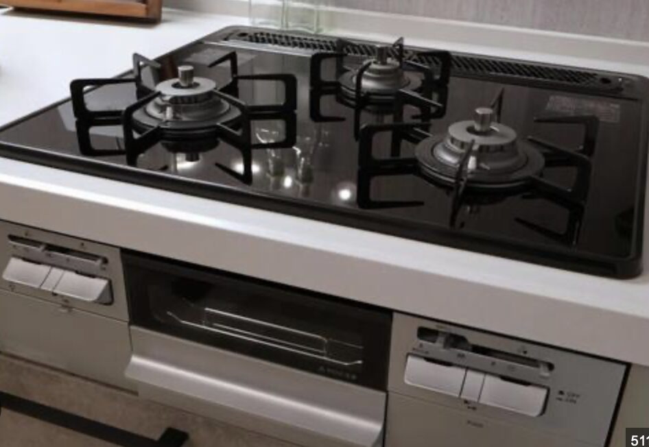 ガラストップ仕様のビルトインガスコンロを斜め上から撮影した写真。三口バーナーとグリル付きの一体型タイプ。