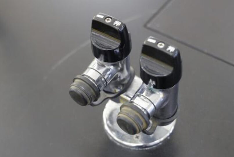 二つのガス栓(元栓)を写した写真。黒いレバー付きで、金属配管に接続されている状態。