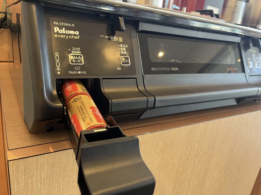 パロマ製ガスコンロの前面電池ケースを引き出し、単1アルカリ乾電池を交換している様子。