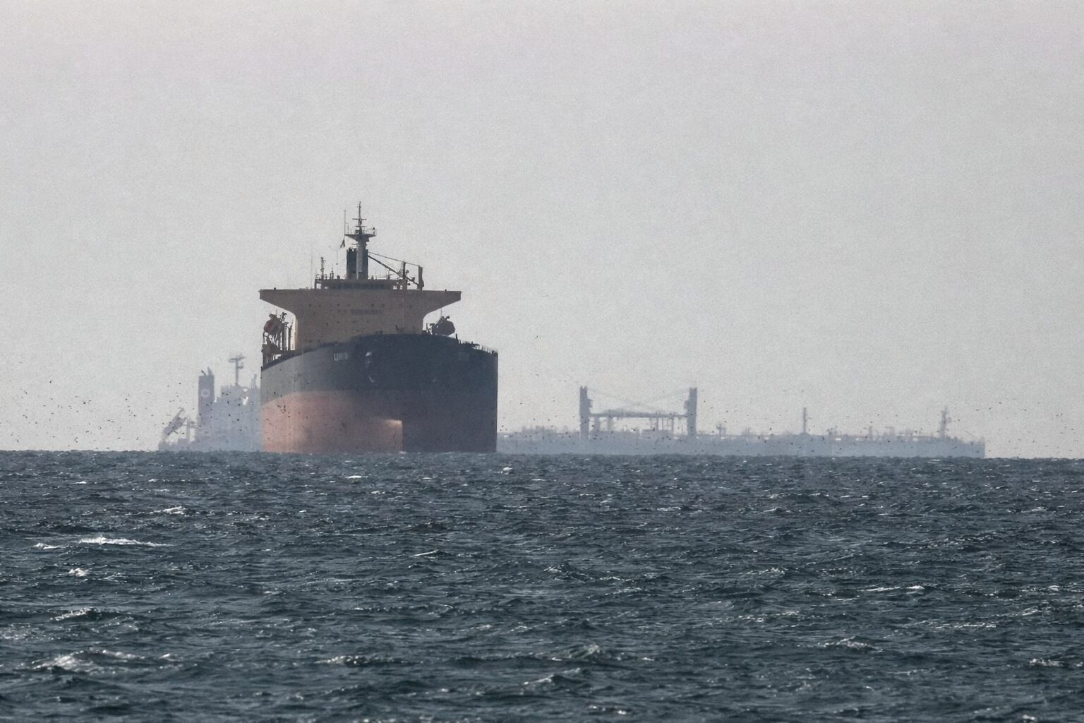 外洋を航行する大型タンカーと遠くに見える貨物船、手前には波立つ海面が広がる海上輸送の風景