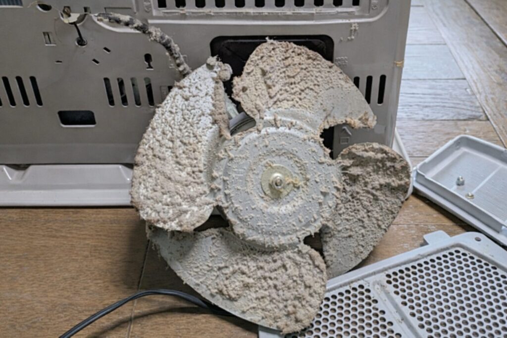 内部の送風ファンに大量のホコリが付着して詰まっている暖房機器の分解状態