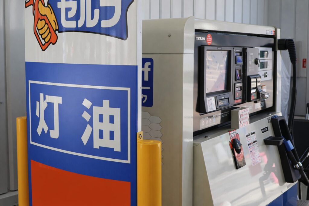 セルフ式の灯油スタンドで「灯油」と書かれた青い看板の横に設置された灯油給油機(タツノ製ディスペンサー)の様子。