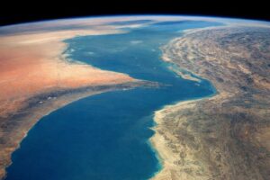 宇宙から見たホルムズ海峡とアラビア半島・イラン沿岸の地形が広がる横長の俯瞰風景