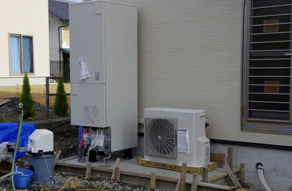 住宅外壁横に設置されたエコキュートの貯湯タンクとヒートポンプユニット