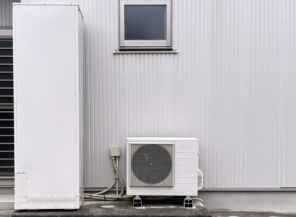 住宅外壁に設置されたエコキュートの貯湯タンクとヒートポンプユニットの設備構成