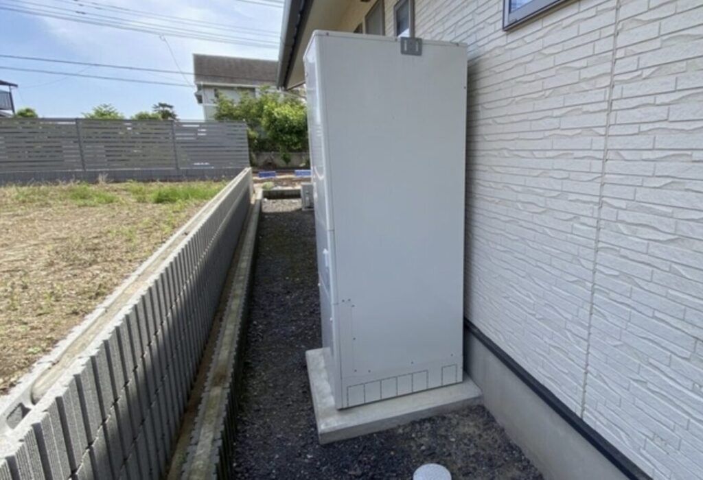 住宅の外壁横に設置されたエコキュートの貯湯タンク