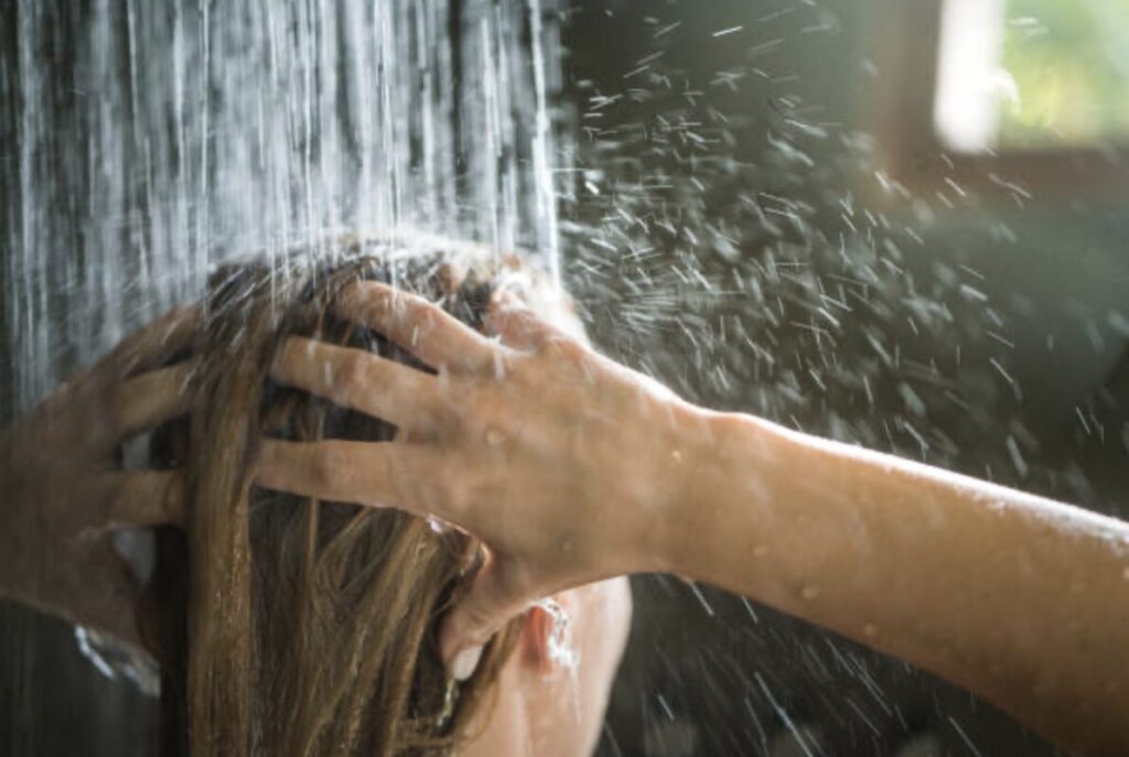髪を洗う人の頭にシャワーを当てている入浴シーン