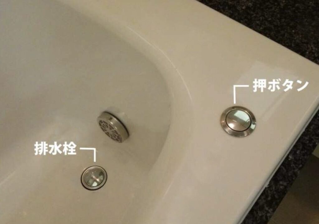 浴槽の排水栓と押しボタン式の排水操作部分を示したバスタブの設備写真