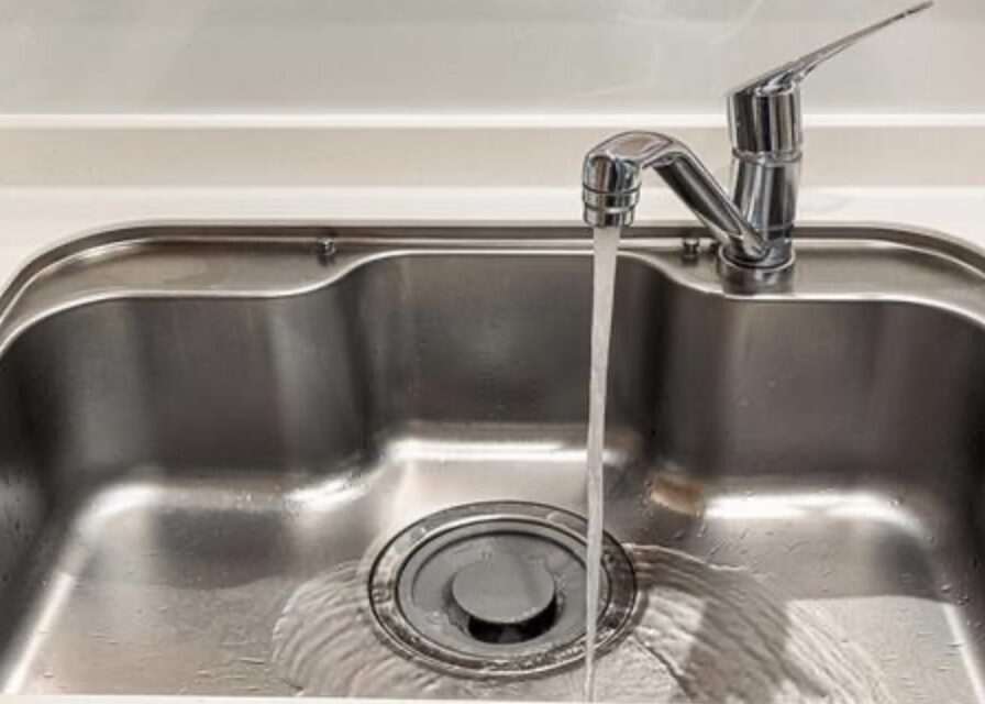キッチンシンクの排水口へ水が流れている台所の流し台