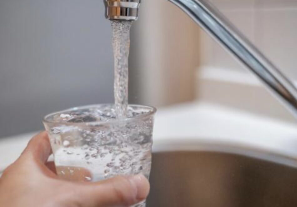 蛇口からグラスに水を注いでいるキッチンの水道