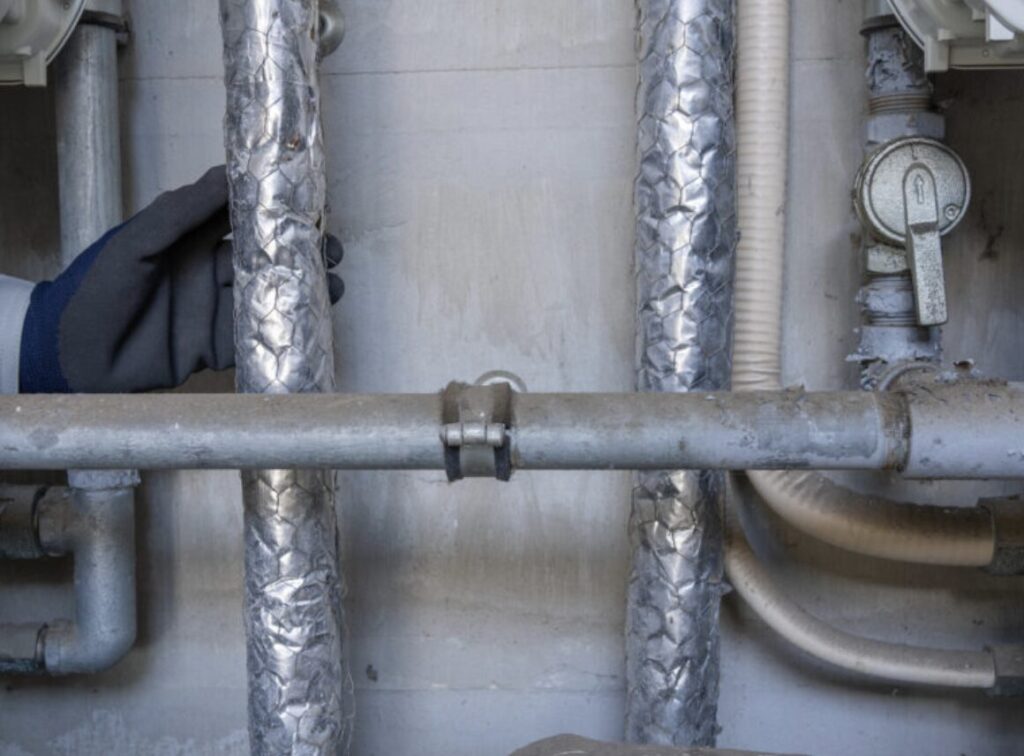 ウォーターハンマーによる振動が発生する給水配管の状態を確認している様子