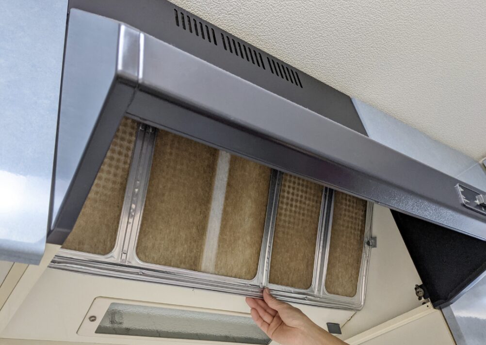 レンジフードの油汚れが付着したフィルターを取り外している様子