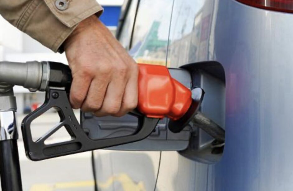 車の給油口に赤い給油ノズルを差し込みガソリンを入れている手元のクローズアップ