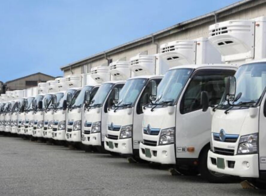 配送用の冷凍トラックが整列している物流会社の車両基地。業務用トラックが多数並ぶ様子。