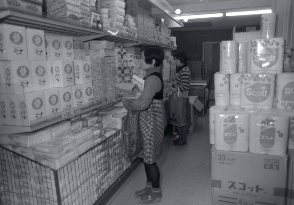 店内の棚に並ぶトイレットペーパーを購入する買い物客の様子