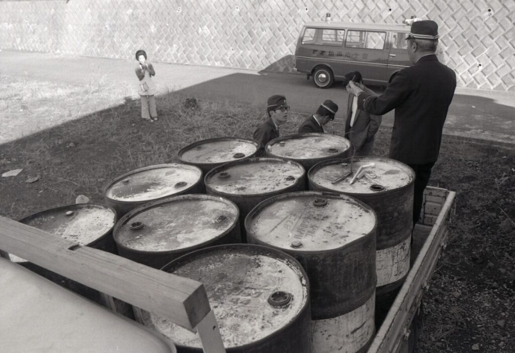 石油ドラム缶を積んだトラックを警察官が確認している様子