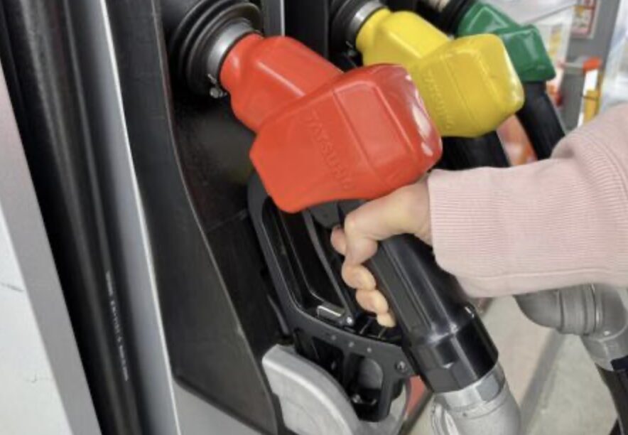 セルフ式ガソリンスタンドで赤い給油ノズルを持ち給油しようとしている手元