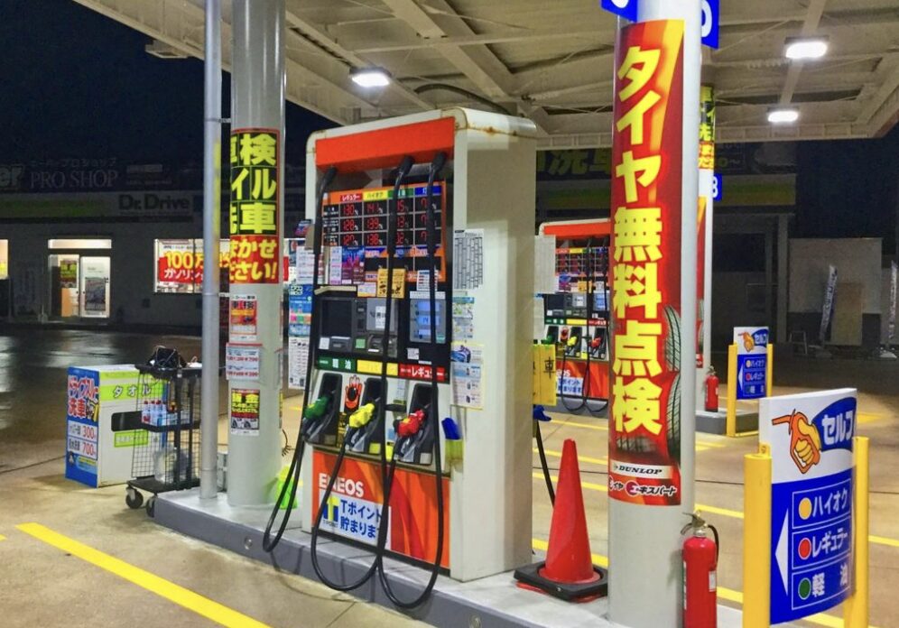 夜間営業のガソリンスタンドで給油機と料金表示が並ぶセルフサービス給油所