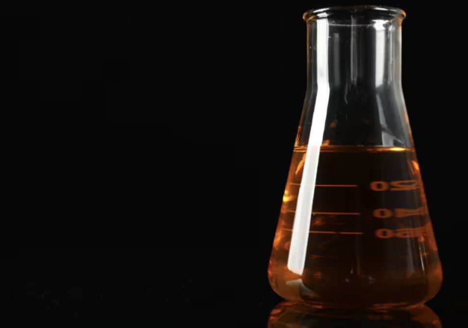 フラスコに入った琥珀色の液体燃料を黒背景で撮影したナフサの実験イメージ
