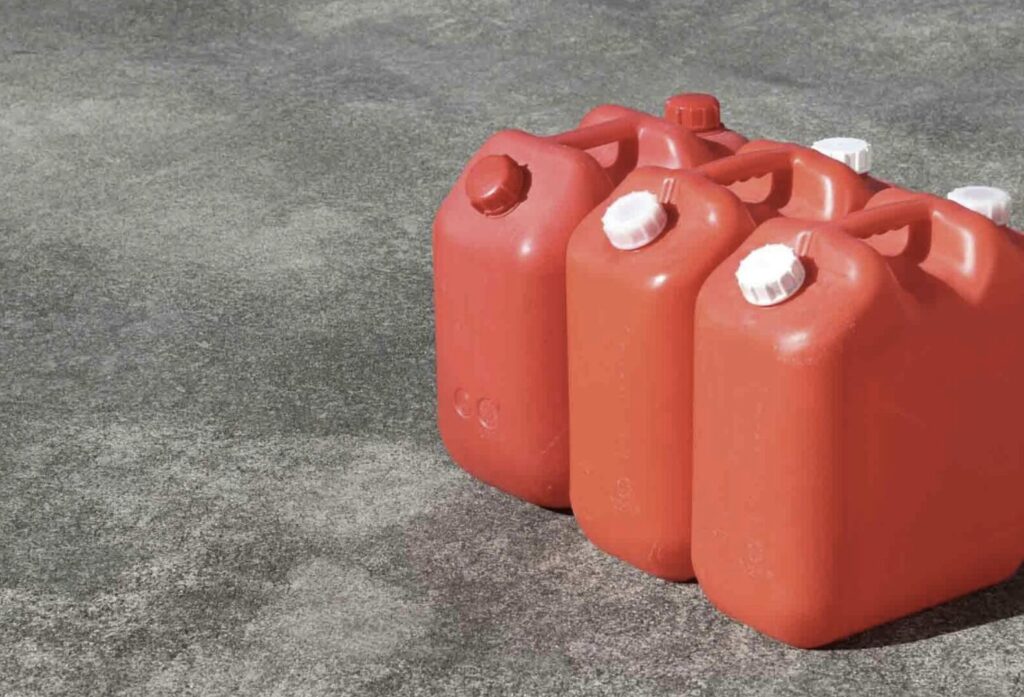赤いポリタンクが屋外の地面に並べて置かれている灯油容器のイメージ