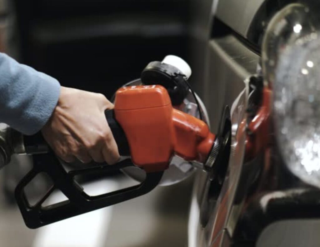 赤い給油ノズルで車に燃料を入れている様子のクローズアップ