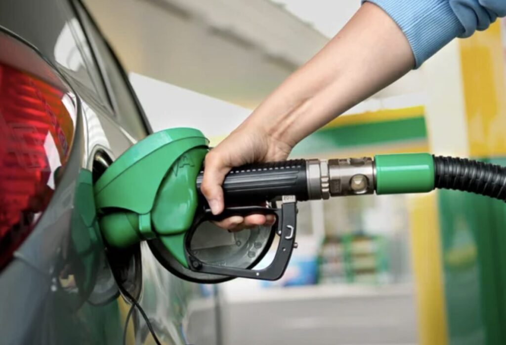 手で給油ノズルを持ち、自動車の給油口に差し込んでいる給油作業の様子