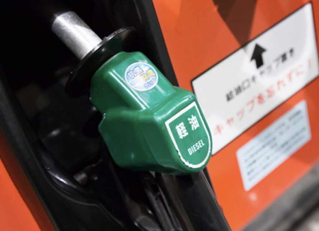 軽油ノズルを給油機に差し込んだ状態のクローズアップで、ディーゼル燃料を示す表示が見える様子