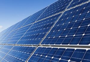 青空の下で太陽光パネルが並ぶ発電設備を斜めから捉えたクリーンエネルギーのイメージ