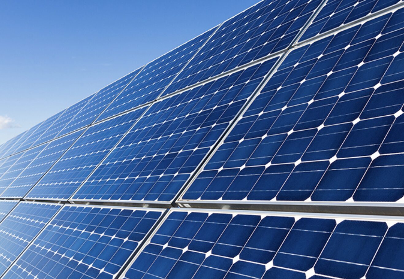 青空の下で太陽光パネルが並ぶ発電設備を斜めから捉えたクリーンエネルギーのイメージ