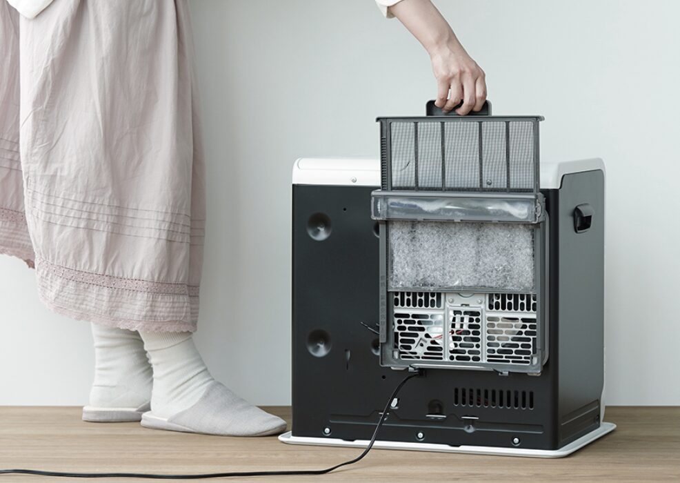 石油ファンヒーターの背面フィルターを取り外して掃除している様子