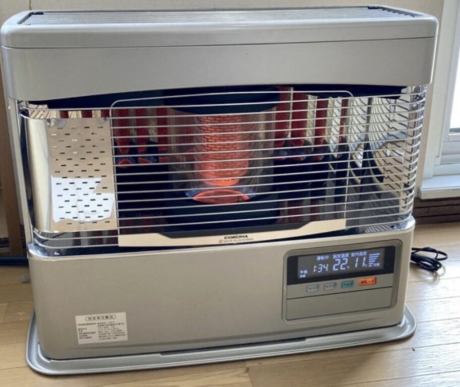 赤く燃焼している反射式の石油ストーブ本体と操作パネルが見える暖房機器の写真