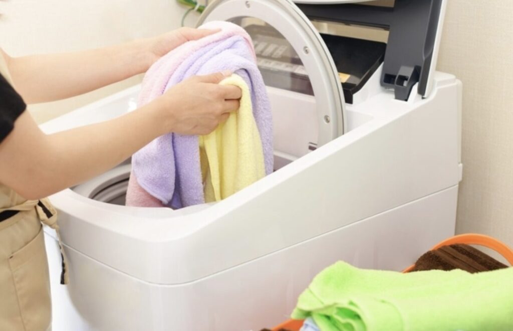洗濯機にタオルを入れて洗濯している様子