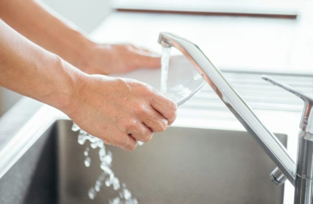 キッチンのシンクで水を流しながら食器を洗っている手元の様子