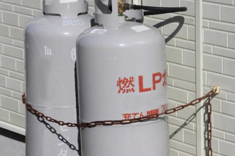 住宅の外壁に設置されたLPガスボンベと固定チェーンの様子