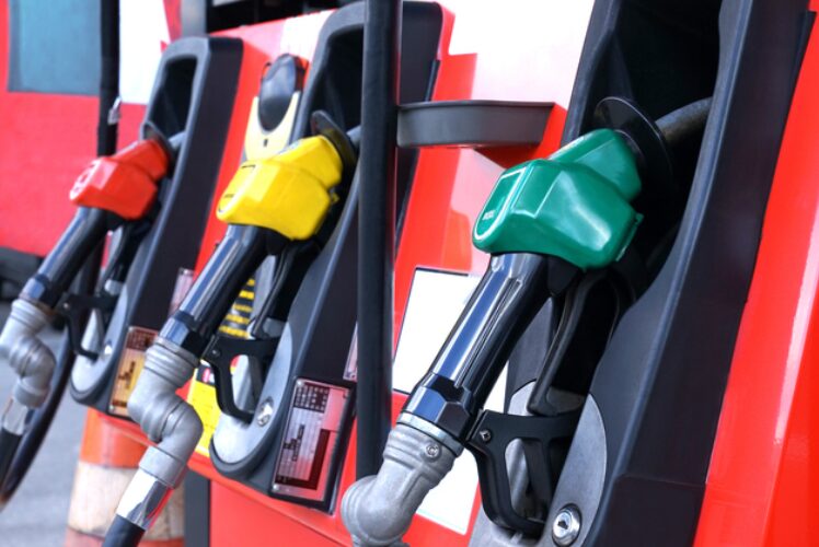 ガソリンスタンドの給油機に並ぶ赤・黄・緑の給油ノズルの様子