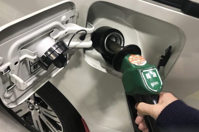 自動車に軽油を給油している手元と給油口のクローズアップ