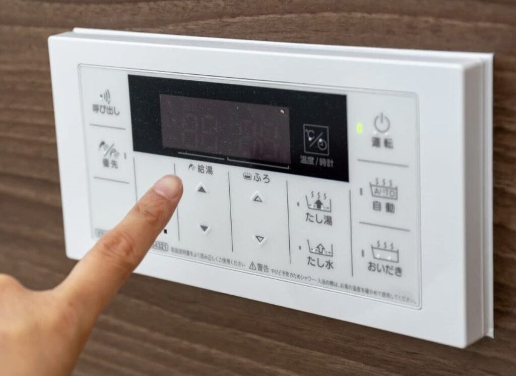 給湯器リモコンの操作パネルを指で操作している様子
