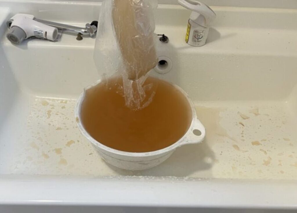 洗面台でフィルターを通した茶色い水をボウルに溜めている様子