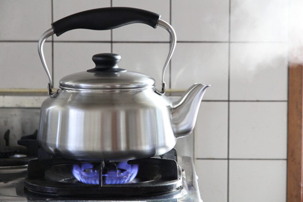 ガスコンロの青い炎でやかんのお湯を沸かしている様子