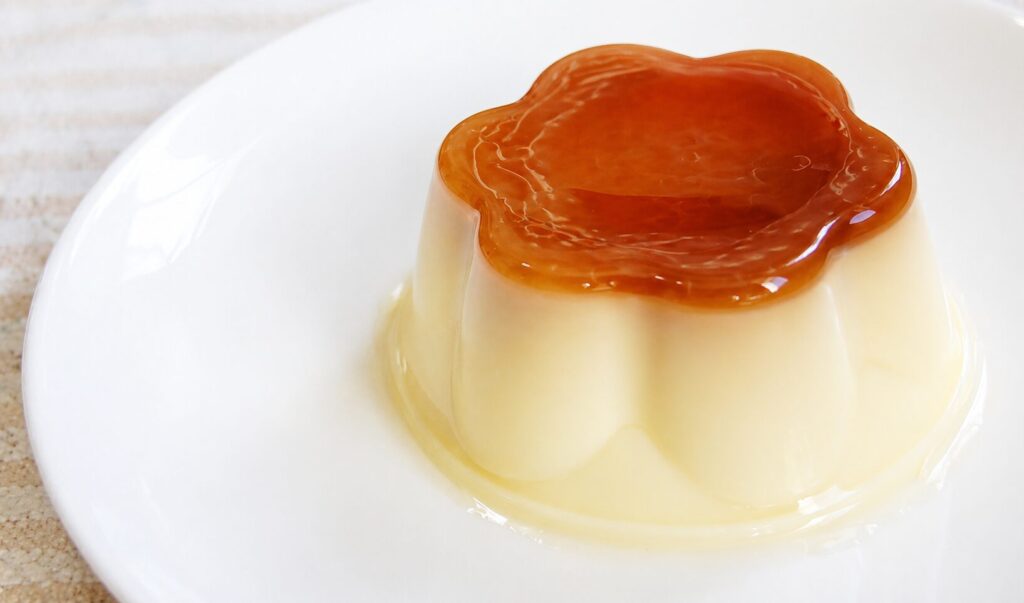 白い皿の上に盛られたなめらかなプリンに、艶のあるカラメルソースがかかった様子